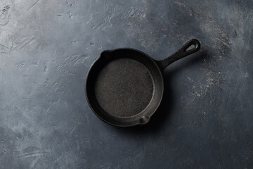 Small cast iron pan on a dark concrete background, place for text