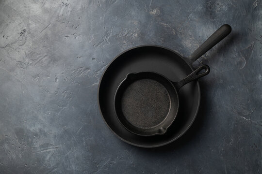 Two cast iron pans on a dark concrete background, place for text