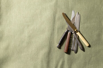 Vintage knives for fruit on an olive-colored linen tablecloth, space for text