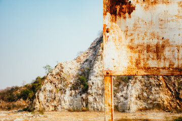 Old rusty blank metal sign in front limestone mountains background in Thailand. Limestone mountain texture.
