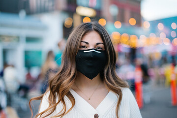 Young woman smiling wearing black mask on city street