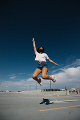 Young woman wearing mask jumping in air on parking garage