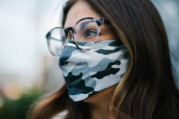 Close up of young woman with glasses wearing camo mask