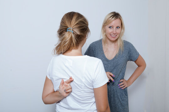 Mother asking her teenage daughter. Girl wants to lie to her parent and crossed her fingers.