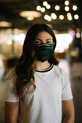 Young brunette woman smiling wearing green mask in urban open food market