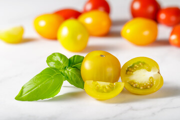 Yellow cherry tomatoes and basil on marble table
