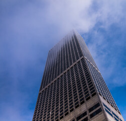 An office tower disappears into the clouds and blue sky.