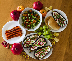 Grilled eggplants, salad, caramelized carrots and fresh fruits on wooden table. Top view photo of different vegetarian meals. 