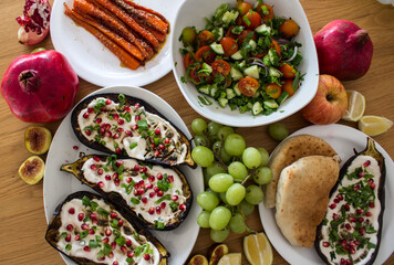Grilled eggplants, salad, caramelized carrots and fresh fruits on wooden table. Top view photo of different vegetarian meals. 