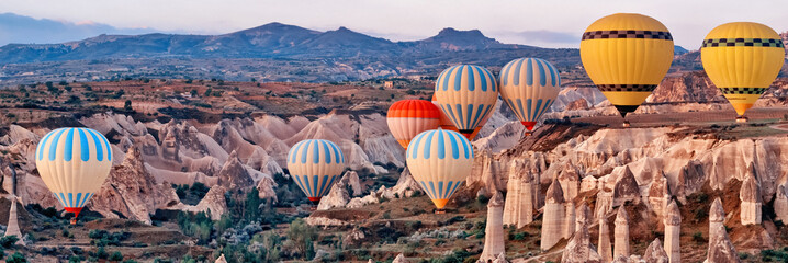 Hot air balloons over mountain landscape in Cappadocia, Turkey.