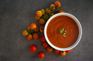 Gazpacho soup top view photo. Dark grey textured background with copy space. Healthy eating concept. 
