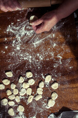 Cooking homemade dumplings or ravioli with meat on the table. Women's hands make dumplings.