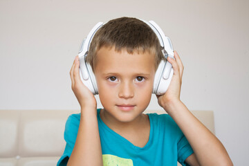 Little boy in blue shirt wearing earphones Child enjoys music.