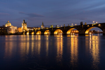 Fototapeta na wymiar illuminated stone monument of Charles Bridge from the 14th century on the Vltava river and lights from street lighting in the center of Prague