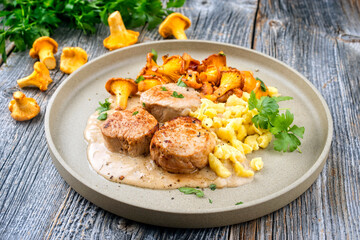Modern Style traditionelle gebratene Filet Medaillons vom Schwein in Rahmsauce mit Spätzle angeboten als close-up auf einem Nordic Design Teller