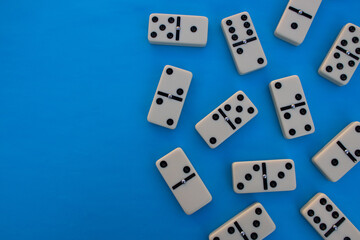 Deck of scattered dominoes on vibrant blue background. Top down view flat lay with empty space for text