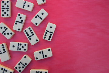 Deck of scattered dominoes on vibrant red background. Top down view flat lay with empty space for text