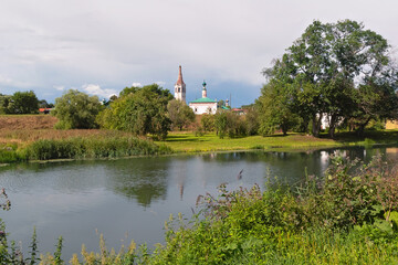 Fototapeta na wymiar Summer river landscape with churches in the distance in Suzdal. Golden ring of Russia