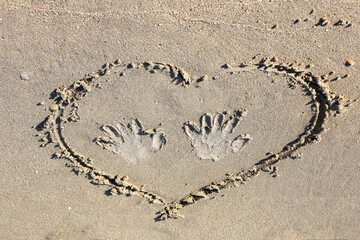 heart on the sand with hand prints