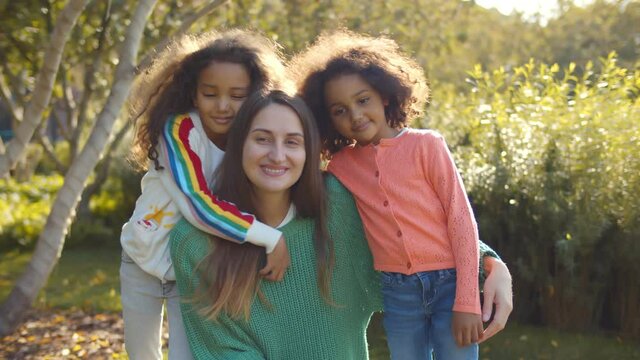 Caucasian young mom and afro daughters hugging in park