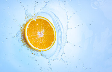 Fototapeta na wymiar Fresh ripe half of orange fruit splashing into clear water.