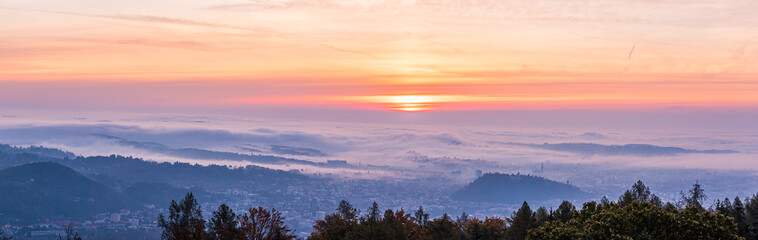 Panorama of Graz city covered if fog on autumn morning during sunraise.