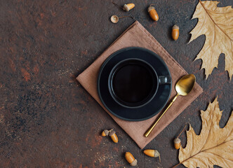 Fototapeta na wymiar Autumn still life with coffee, acorns and leaves. Acorn coffee in a black cup on a brown background. Copy space, top view, flat lay.