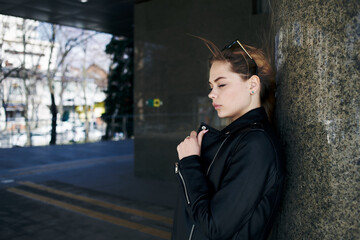 woman in leather jacket on the street in the city and edition sunglasses in the background