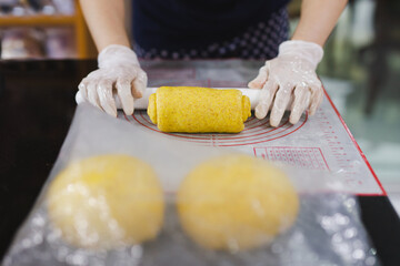 Woman hands kneading dough making bread with a rolling pin.