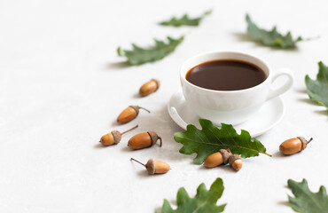 Obraz na płótnie Canvas Cozy still life with a cup of coffee, oak leaves and acorns on a white background. Acorn coffee. Caffeine free. Copy space