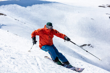 Fototapeta na wymiar A man is skiing down the hill on the steep slope.