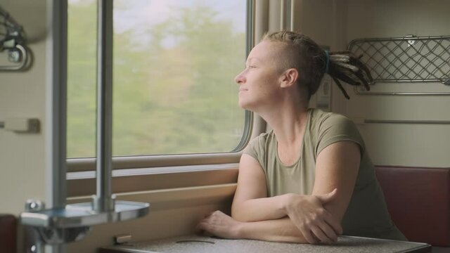woman passenger rides train and looks out window.