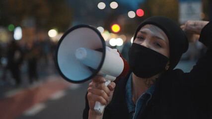 A young girl in a medical mask speaks through a loudspeaker. Protest against abortion, protecting...
