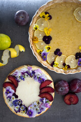 Lemon tart and cheesecake decorated with edible flowers on yellow fabric background. Sweet food top view photo. 
