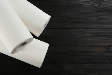 Rolls of paper towels on wooden table, flat lay. Space for text