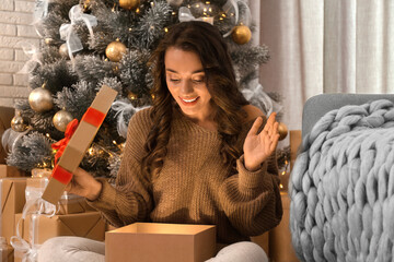 Happy young woman opening Christmas gift at home. Magic holiday