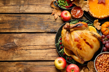 Traditional Thanksgiving day feast with delicious cooked turkey and other seasonal dishes served on wooden table, flat lay. Space for text - obrazy, fototapety, plakaty