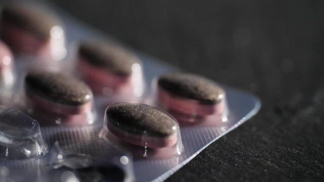 4K Close up of medical pills in an opened package. Rotating macro video of remaining pharmaceutical supplements in an almost empty container. A symbol of health but also an addiction to medicine.