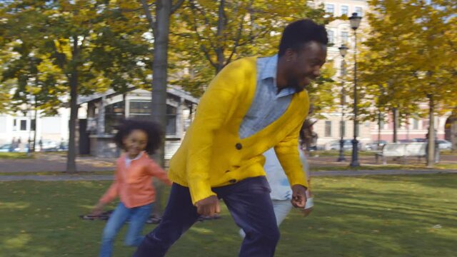 African father and little daughters playing on green grass in autumn park
