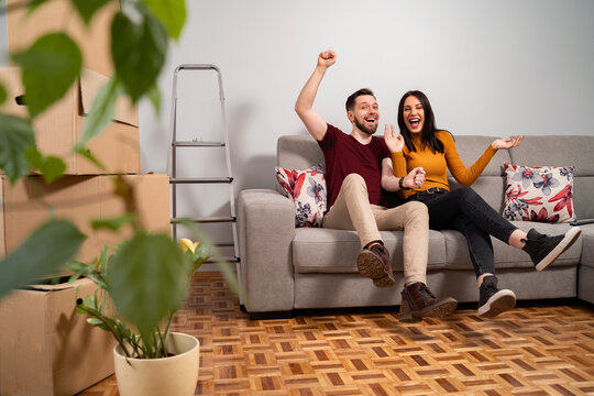 Happy couple on sofa celebrating moving to a new home 