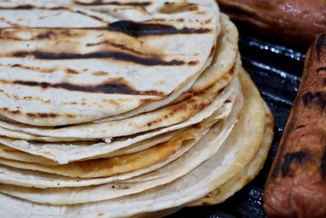 View of some mexican tortillas with fried saussages on a grill
