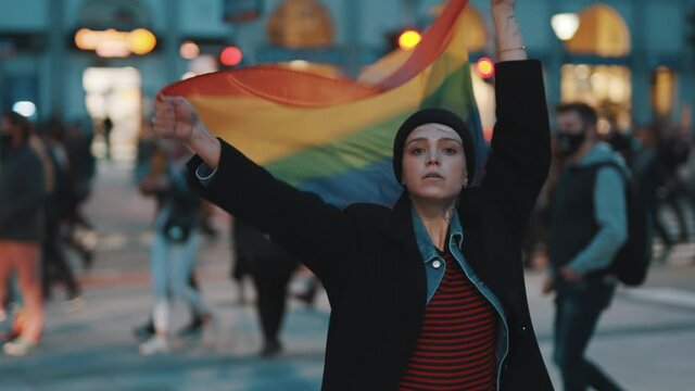 Young woman on the protest waving rainbow pride flag. Demonstrations during covid-19 outbreak and demand for equal rights. High quality 4k footage