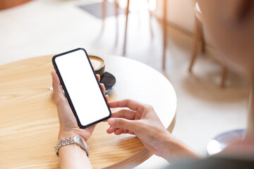 cell phone blank white screen mockup.woman hand holding texting using mobile on desk at coffee shop.background empty space for advertise.work people contact marketing business,technology