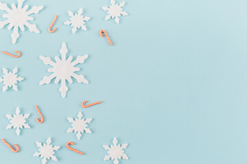 Christmas composition. Snowflakes, red and white candies on blue background. Christmas, winter, new year concept. Minimal style. Flat lay, top view, copy space.