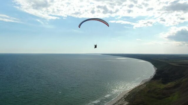 Landscape view on the sea and a person paragliding, aerial shot