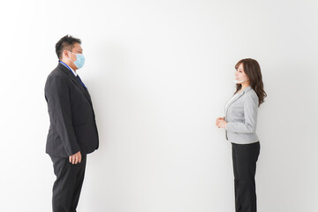 ソーシャルディスタンスを確保し、オフィスで会話をするビジネスパーソン
