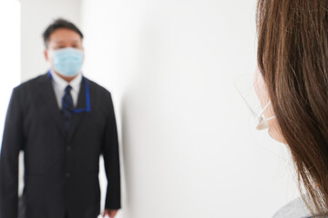ソーシャルディスタンスを確保し、オフィスで会話をするビジネスパーソン