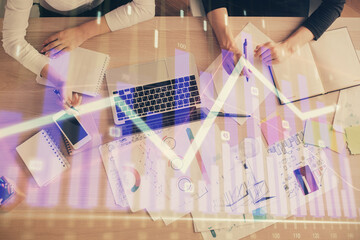 Double exposure of woman hands working on computer and forex graph hologram drawing. Top View. Financial analysis concept.