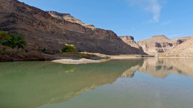 Panning the Green River at Nefertiti as the cliffs reflect in the water on sunny day in Utah.