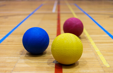 Gros plan de trois ballons de différentes couleurs dans un gymnase
